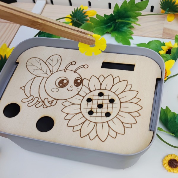 Insert en bois abeille et tournesol dans un bac sensoriel, utilisé avec une pince et un jeton jaune