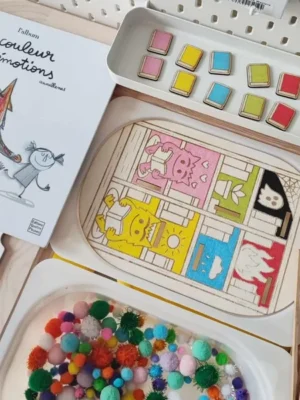 Activité sensorielle en bois inspirée du livre “La couleur des émotions” avec livres colorés à associer et pompons tactiles