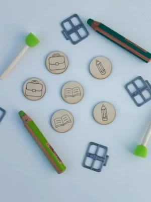 Jetons en bois gravés de pictogrammes scolaires entourés d’accessoires éducatifs pour activités Montessori