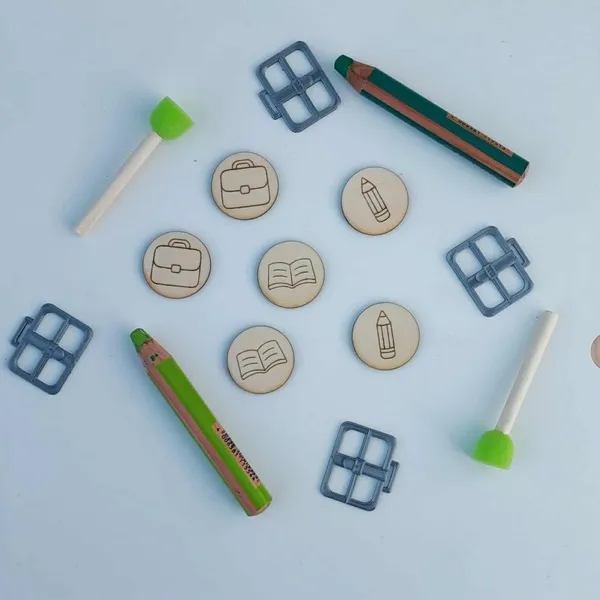 Jetons en bois gravés de pictogrammes scolaires entourés d’accessoires éducatifs pour activités Montessori