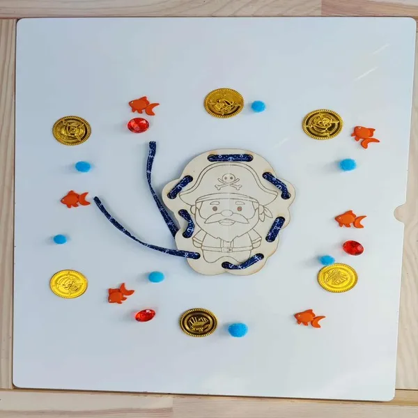 Carte à lacer pirate en bois au milieu de pièces d’or et poissons pour activité Montessori