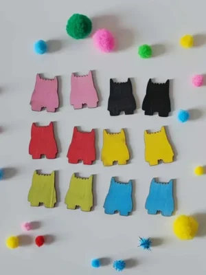 Petits jetons en bois colorés en forme de monstres disposés en rangées avec des pompons sensoriels autour