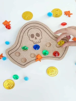 Enfant jouant avec un chapeau de pirate en bois rempli de pierres précieuses colorées