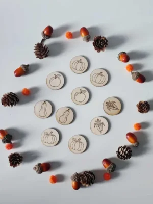 Jetons en bois gravés de légumes et fruits d’automne entourés de pommes de pin, glands et pompons sensoriels