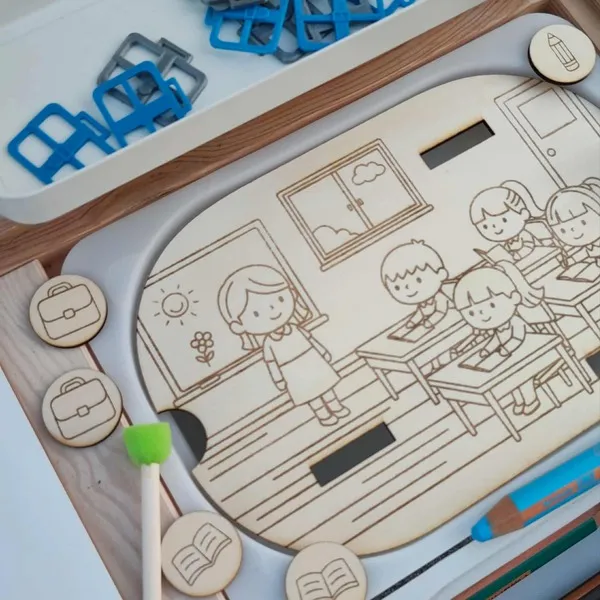 Insert en bois Montessori représentant une salle de classe avec jetons cartable, livre et crayon