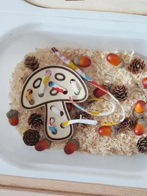 Carte à lacer en bois en forme de champignon utilisée dans un bac sensoriel d’automne Montessori
