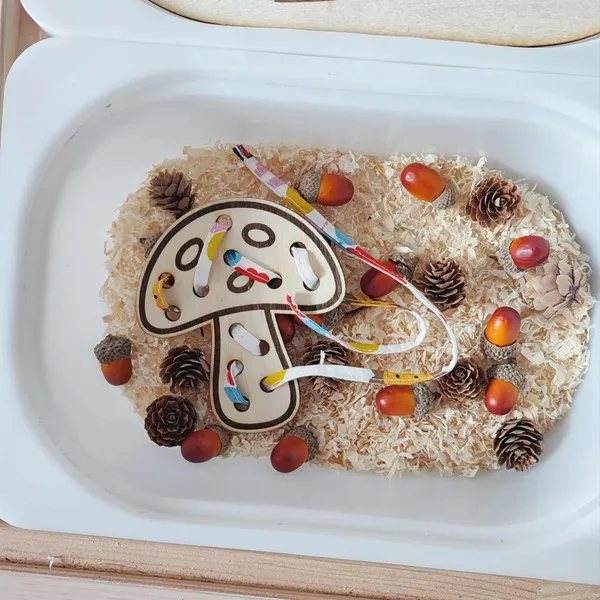 Carte à lacer en bois en forme de champignon utilisée dans un bac sensoriel d’automne Montessori