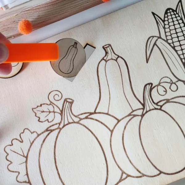 Main d’enfant manipulant un jeton de courge sur un plateau sensoriel en bois thème automne Montessori