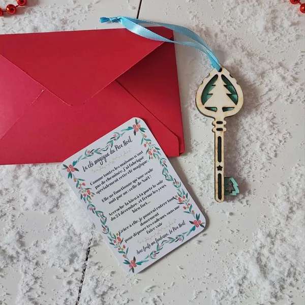 Clé magique du Père Noël en bois sapin bleu avec ruban, carte explicative et enveloppe rouge sur fond enneigé de décor de fête