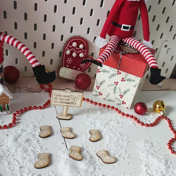 Décor de Noël avec lutins farceurs et jeu en bois concours de lancer de chaussettes sur fond enneigé et guirlande rouge