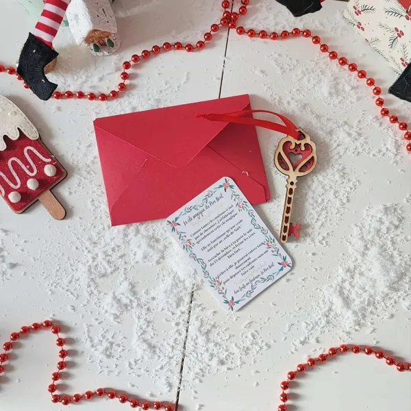 Clé magique du Père Noël en bois avec cœur rouge, carte explicative et enveloppe rouge dans un décor de Noël enneigé avec guirlande et décorations festives