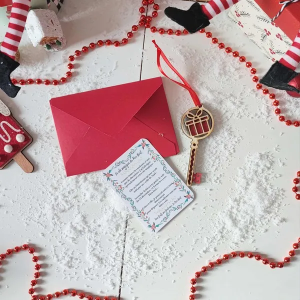 Clé magique du Père Noël en bois motif cadeau rouge avec carte explicative et enveloppe rouge dans un décor enneigé et festif de Noël