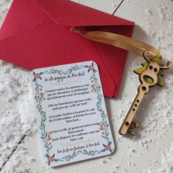 Clé magique du Père Noël en bois avec ruban doré, carte explicative et enveloppe rouge sur fond enneigé décoratif
