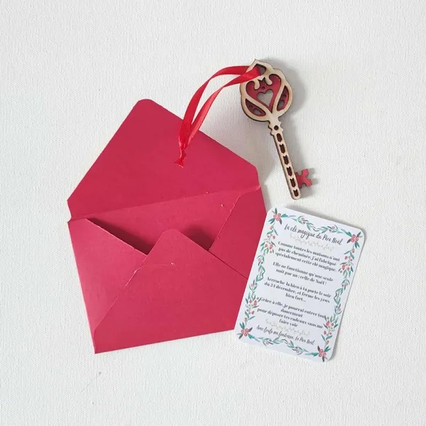 Clé magique du Père Noël en bois avec motif cœur rouge, ruban assorti, carte explicative et enveloppe rouge sur fond clair