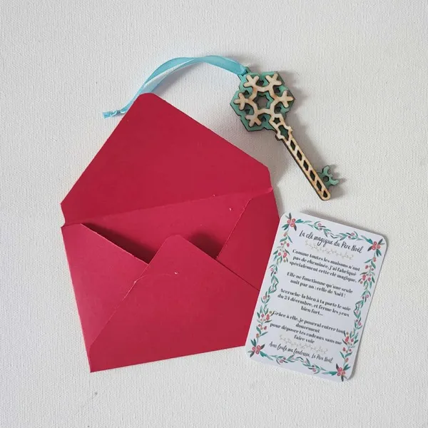Clé magique du Père Noël en bois décorée d’un flocon bleu, accompagnée d’une carte explicative et d’une enveloppe rouge sur fond clair