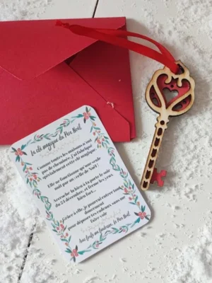 Clé magique du Père Noël en bois motif cœur rouge avec carte explicative et enveloppe rouge sur fond enneigé