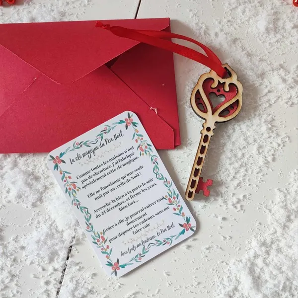 Clé magique du Père Noël en bois motif cœur rouge avec carte explicative et enveloppe rouge sur fond enneigé