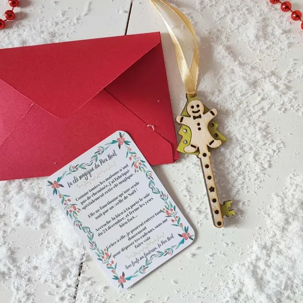 Clé magique du Père Noël en bois décorée d’un bonhomme pain d’épices avec carte explicative et enveloppe rouge sur fond enneigé