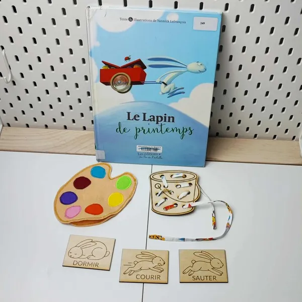 Activité éducative inspirée du livre “Le Lapin de printemps” avec cartes en bois illustrant les verbes d’action et jeux sensoriels
