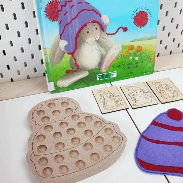 Activité éducative inspirée du livre “Le Bonnet de Lapinus” avec plateau de motricité fine en bois, cartes gravées et bonnet en feutrine colorée