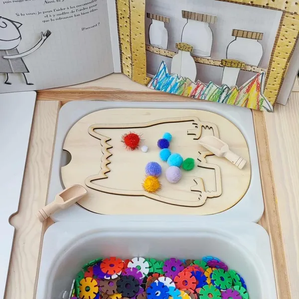 Insert en bois représentant le Monstre des émotions avec pompons colorés et outils de motricité fine sur table sensorielle