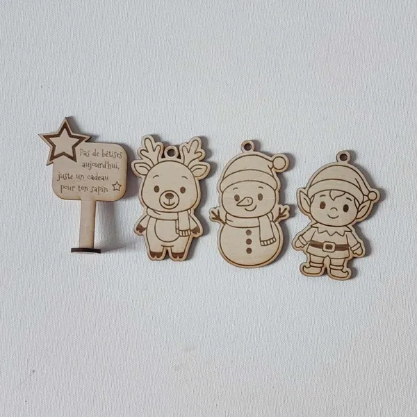 Décorations de Noël en bois gravé représentant un renne, un bonhomme de neige, un lutin et un panneau “Pas de bêtises aujourd’hui, juste un cadeau pour ton sapin”