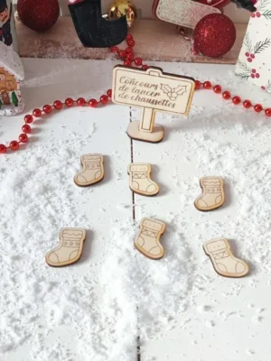 Jeu de Noël en bois concours de lancer de chaussettes présenté dans un décor enneigé avec guirlande rouge et maison pain d’épice