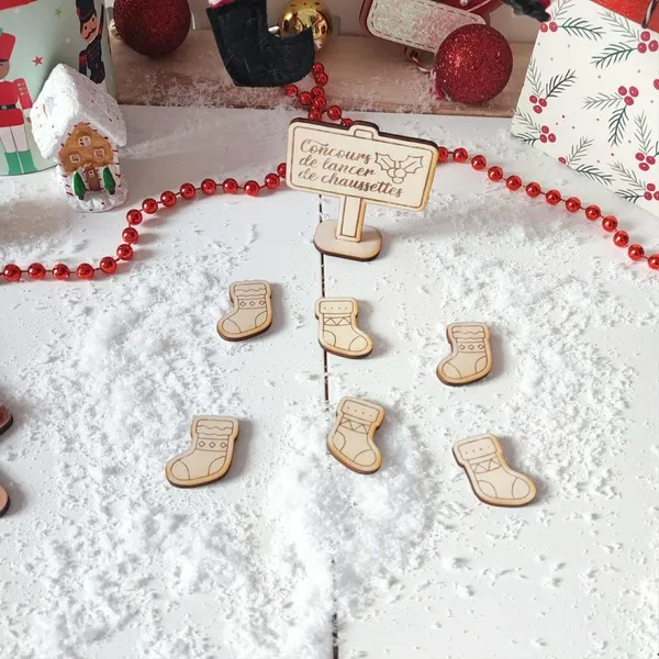Jeu de Noël en bois concours de lancer de chaussettes présenté dans un décor enneigé avec guirlande rouge et maison pain d’épice