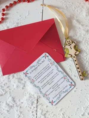 Clé magique du Père Noël en bois motif bonhomme pain d’épices avec carte explicative et enveloppe rouge sur un fond enneigé décoratif