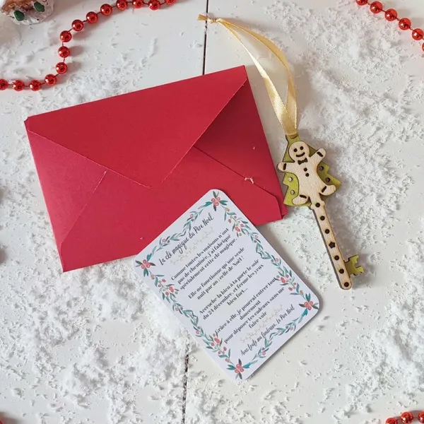 Clé magique du Père Noël en bois motif bonhomme pain d’épices avec carte explicative et enveloppe rouge sur un fond enneigé décoratif