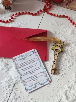 Clé magique du Père Noël en bois avec ruban doré, carte illustrée et enveloppe rouge sur fond enneigé et décorations de Noël