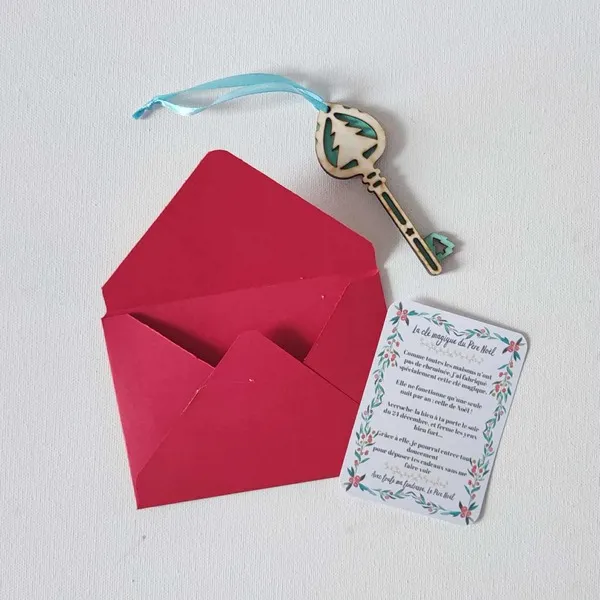 Clé magique du Père Noël en bois décorée d’un sapin bleu, accompagnée d’une carte explicative et d’une enveloppe rouge sur fond clair