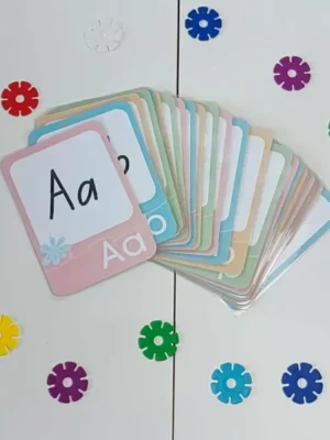 Cartes alphabet pastel plastifiées disposées sur une table blanche, support d’apprentissage des lettres pour enfants inspiré de la pédagogie Montessori