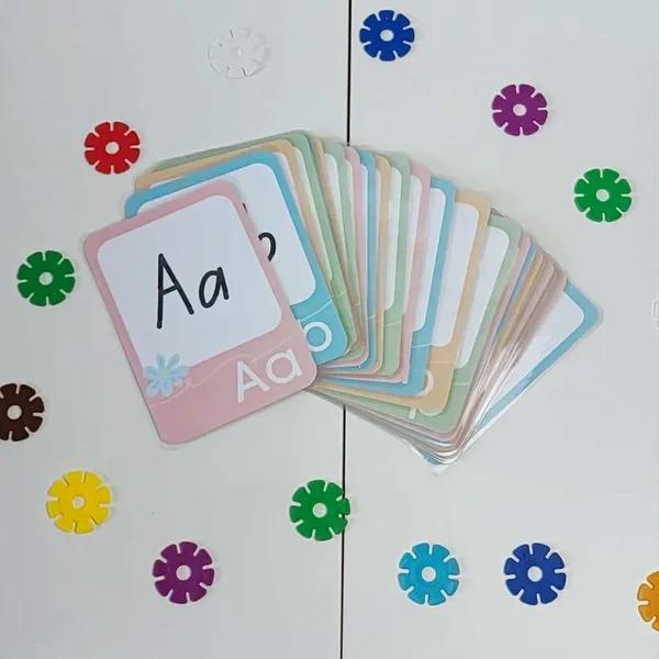 Cartes alphabet pastel plastifiées disposées sur une table blanche, support d’apprentissage des lettres pour enfants inspiré de la pédagogie Montessori