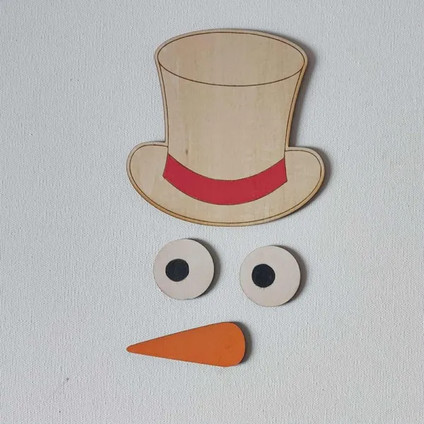 Éléments en bois représentant le visage d’un bonhomme de neige avec chapeau beige à ruban rouge, yeux ronds et nez carotte orange