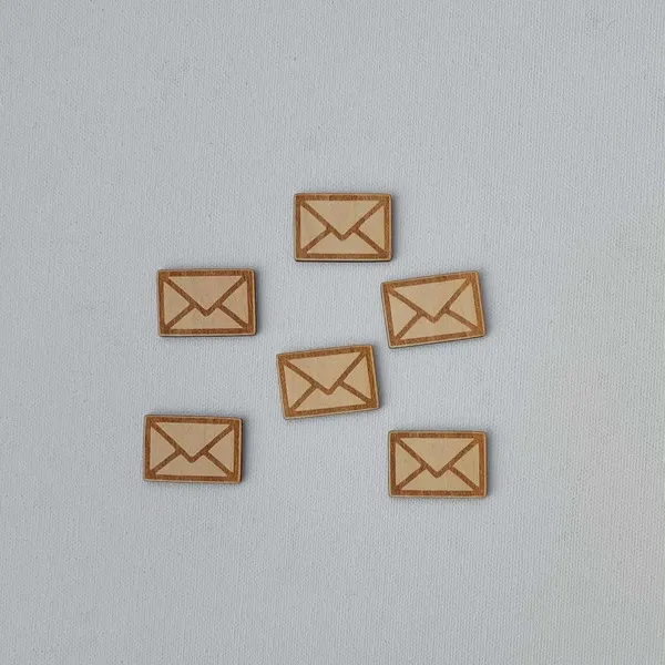 Six mini lettres en bois gravées disposées sur fond clair, accessoires du plateau facteur du Père Noël pour activité Montessori et motricité fine