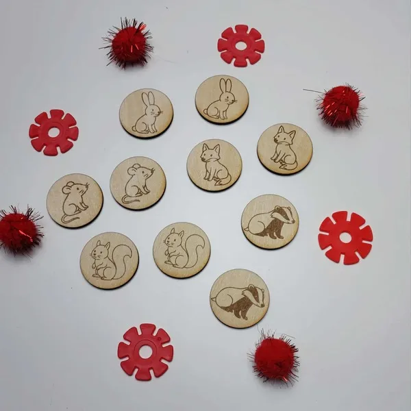 Jetons en bois gravés représentant les animaux de l’histoire La Moufle, entourés d’éléments rouges sensoriels.