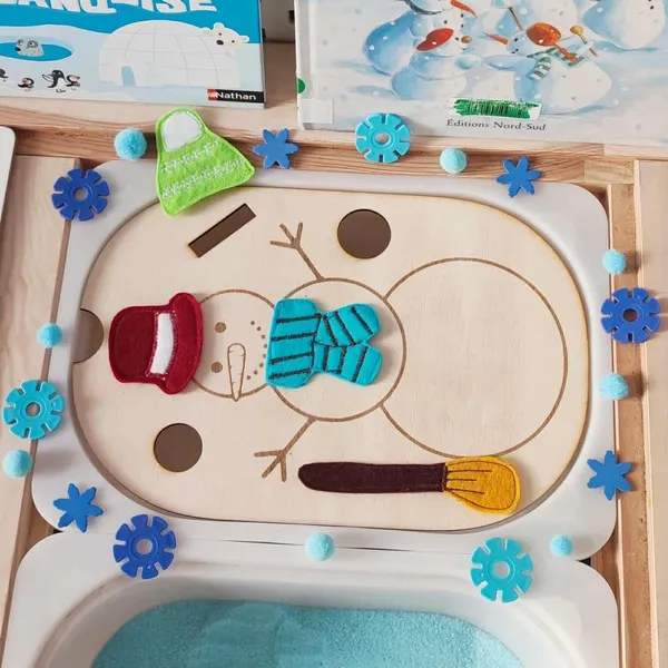 Insert en bois représentant un bonhomme de neige à décorer avec accessoires en feutrine colorée sur plateau sensoriel d’hiver
