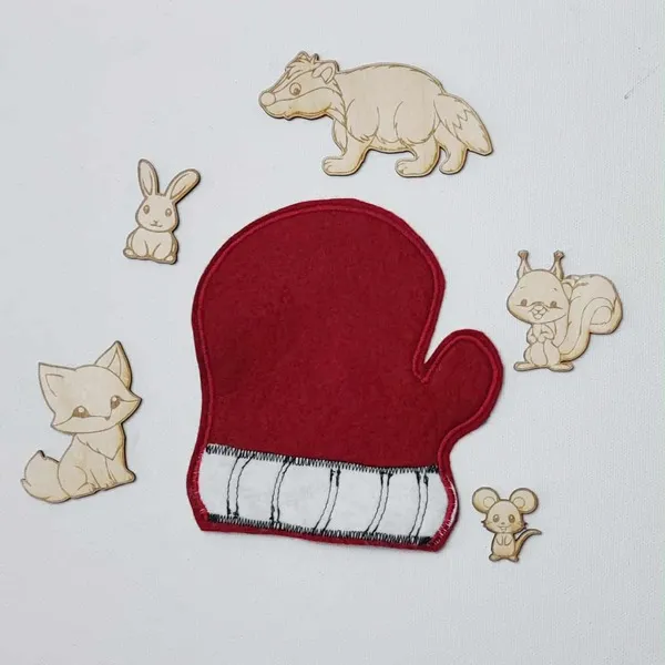 Moufle en feutrine rouge entourée d’animaux en bois gravé issus du conte La Moufle.
