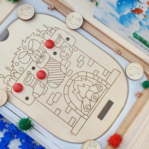 Gros plan sur un plateau en bois gravé représentant une cheminée de Noël avec chaussettes suspendues et jetons à placer – activité Montessori motricité fine