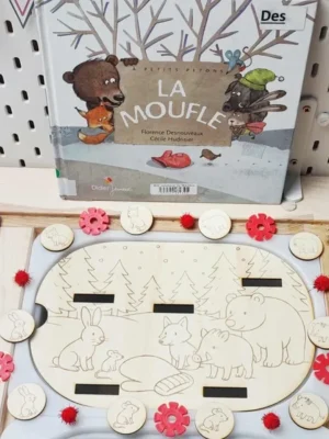 Plateau en bois thème La Moufle avec animaux gravés et jetons assortis, présenté devant le livre d’histoire