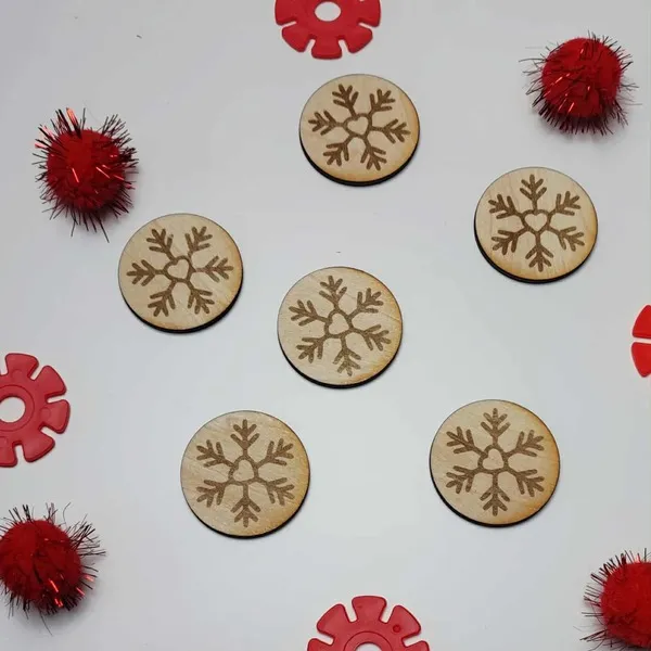 Jetons en bois gravés de flocons d’hiver entourés de pompons rouges et d’éléments sensoriels.