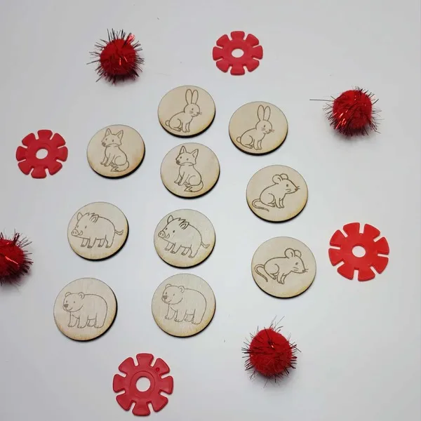 Jetons en bois gravés des animaux du conte La Moufle, présentés en cercle avec pompons et pièces rouges décoratives