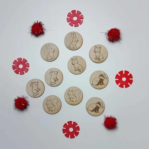 Jetons en bois illustrés d’animaux du conte La Moufle, disposés en cercle avec accessoires rouges.