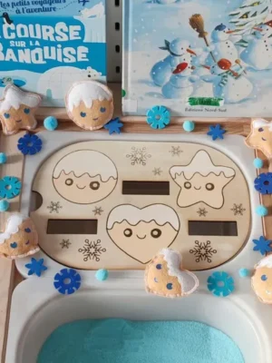 Insert en bois formes d’hiver avec biscuits en feutrine souriants, flocons bleus et sable sensoriel pour activité Montessori