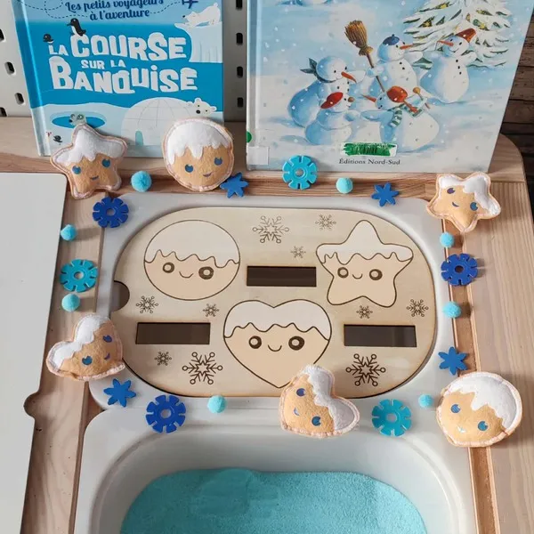 Insert en bois formes d’hiver avec biscuits en feutrine souriants, flocons bleus et sable sensoriel pour activité Montessori