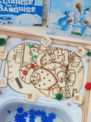 Plateau sensoriel en bois gravé représentant le Père Noël et ses lutins fabriquant des jouets, entouré de pions et accessoires éducatifs sur le thème de Noël