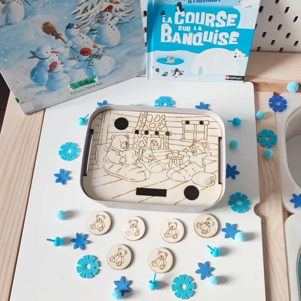 Plateau sensoriel Montessori en bois gravé représentant une famille d’ours polaires lisant près de la cheminée, avec jetons illustrés et décorations d’hiver