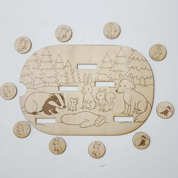 Plateau en bois inspiré du conte La Moufle avec animaux gravés et jetons assortis disposés autour.