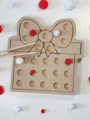 Plateau de motricité fine en bois MDF en forme de cadeau avec nœud, utilisé avec des pompons rouges et blancs et des baguettes sur fond clair